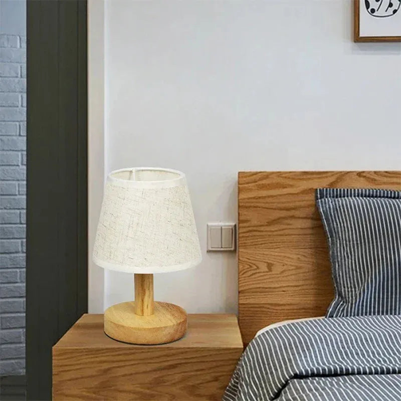 lampe de chevet pied en bois éteinte sur une table de chevet