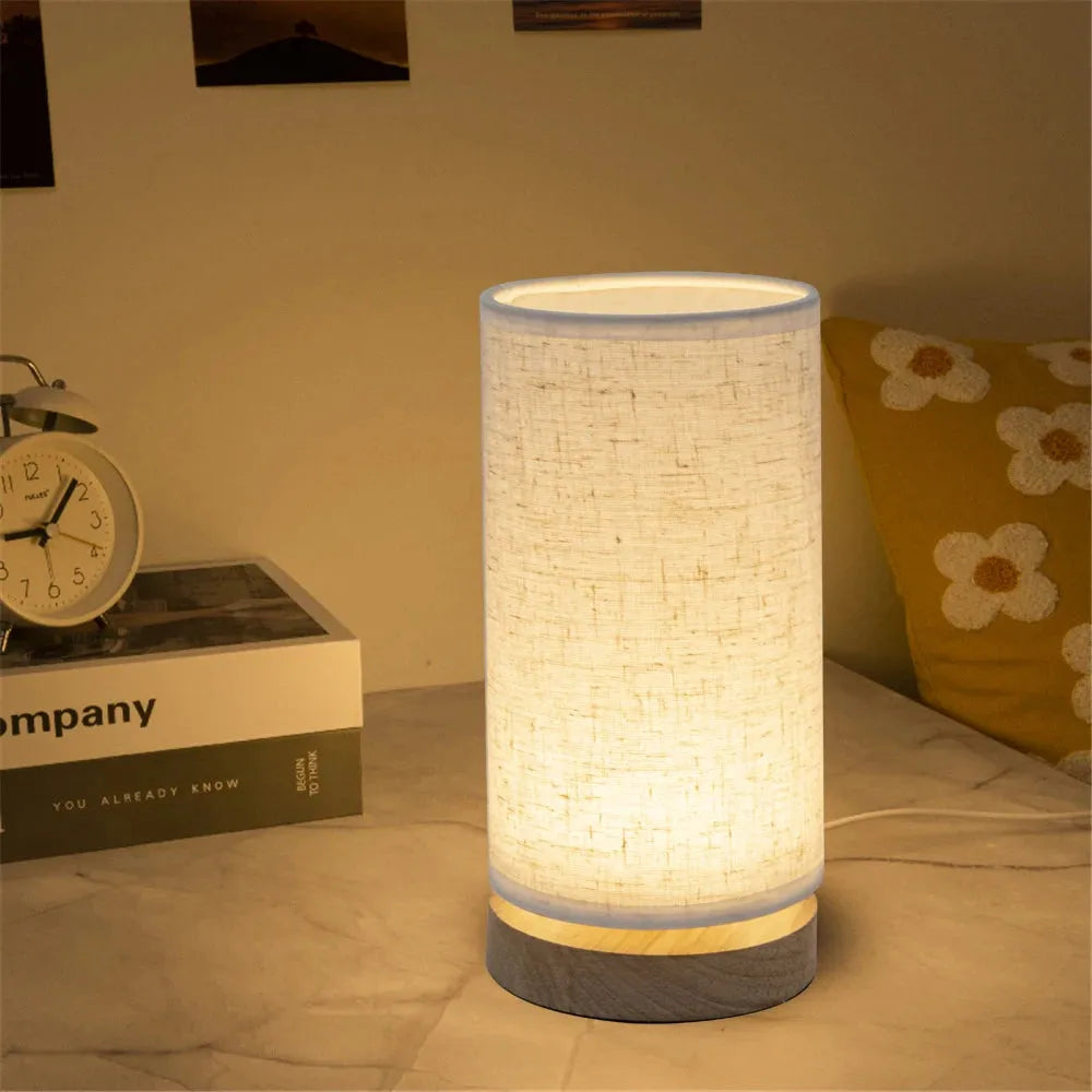 lampe de chevet pied en bois cylindrique sur une table de chevet
