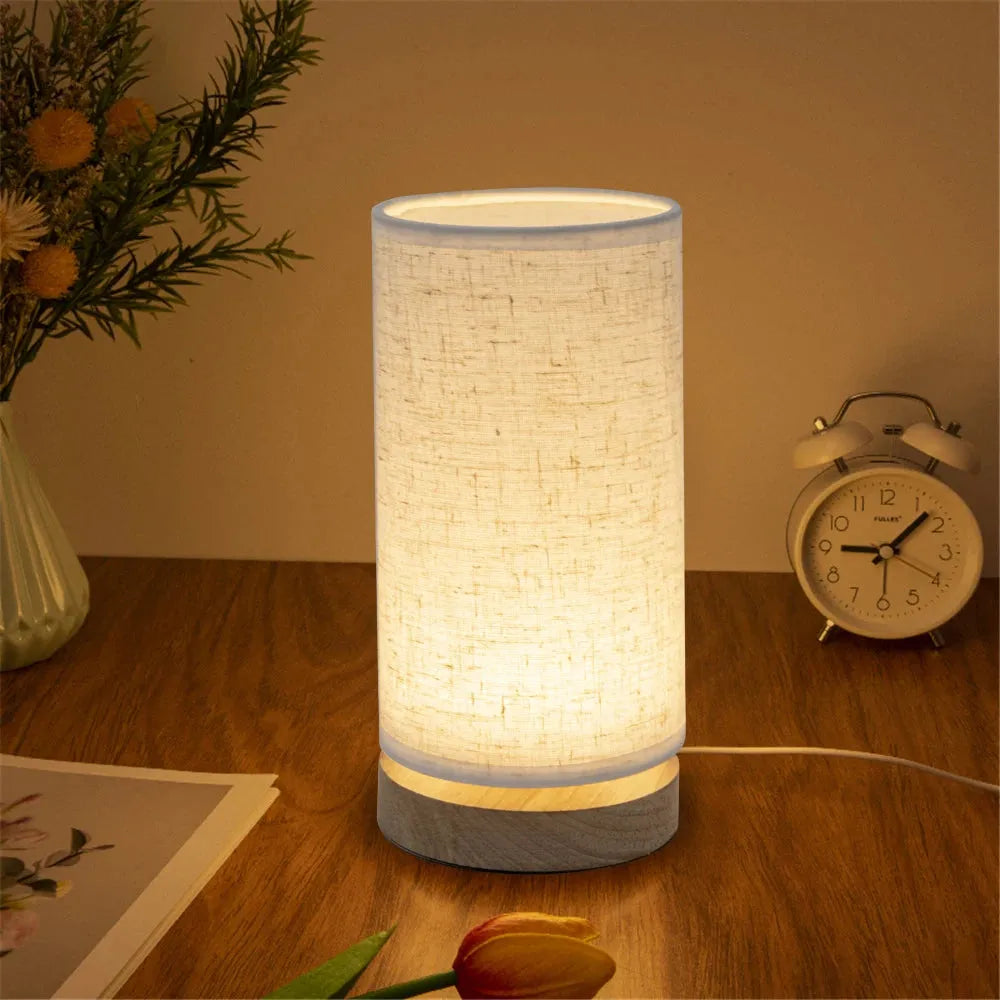 lampe de chevet pied en bois cylindrique sur une table de chevet en bois