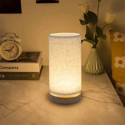 lampe de chevet pied en bois cylindrique sur une table de chevet en marbre